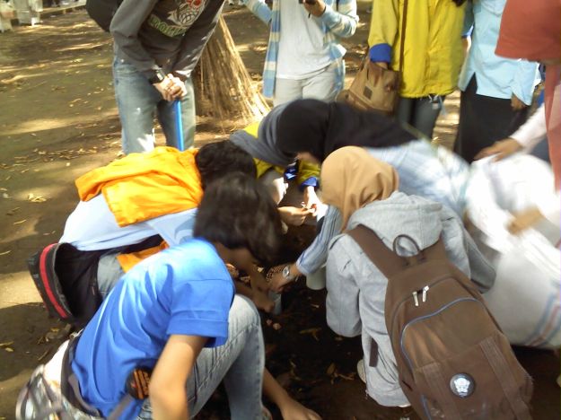 Memasukkan dedaunan ke dalam lubang biopori